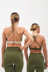 Top deportivo color beige con banda inferior azul y tirantes finos azul marino. Espalda cruzada con doble tira.