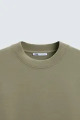 Sudadera relaxed fit color crudo confeccionada en tejido interlock de algodón con elasticidad, cuello redondo, manga corta y bajo acabado en rib.