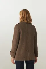 Chaquetón marrón de lana con cuello, abrochadura simple con botón en el cuello, bolsillos ojal y detalle de martingala en mangas.