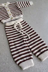 Conjunto tejido artesanalmente en hilado 70% algodón y 30% acrílico, compuesto por un cárdigan a rayas horizontales marrones y beige con botones y un pantalón a juego con cordón en la cintura.