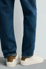 Zapatillas deportivas blancas de caña baja con detalle de color gris en el talón y suela con volumen.