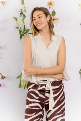 Blusa color beige claro, sin mangas, con cuello tipo camisa y corte holgado con elástico en la cintura.