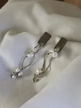 Aros colgantes de alpaca color plateado con perlas de río blancas.