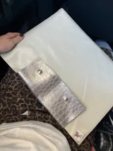 Funda para laptop color dorado con textura símil piel de cocodrilo y solapa color beige con apliques de tachas plateadas.