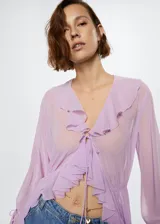 Vestido largo lila semitransparente con cuello en V, volantes en el escote y mangas largas con volantes.