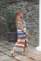 Vestido largo tejido con hilo de algodón a rayas horizontales en tonos marrón, beige, blanco y negro. Tiene cuello redondo y mangas cortas. Tejido a mano con terminaciones en crochet.