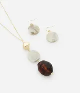 Conjunto de collar largo con cadena dorada y colgantes de resina en tonos marrón, blanco y dorado, acompañado por caravanas anzuelo con colgante de resina.