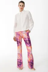 Pantalón de vestir con leve evasé y tajo en laterales, con estampado de flores grandes en tonos violeta y naranja.