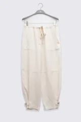 Pantalón color crema de lino y tencel, con bolsillos laterales, cintura elástica y cordón ajustable. Detalle regulable en el tobillo.