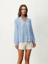 Blusa celeste con cuello mao y escote en V, de mangas largas con puños elásticos.
