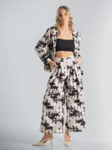 Conjunto de blazer y pantalón elastizado, confeccionado en algodón con lycra y estampa floral en tonos beige, negro y blanco. El pantalón es de corte palazzo y el blazer incluye un aplique floral desmontable.