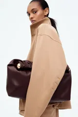Campera color beige de sarga con cuello, cierre oculto adelante y bolsillos laterales con cierre. Modelo de corte holgado con pinzas en los codos para dar forma y cordón para ajustar elástico con topes en el bajo. Sin forrar.