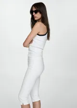 Jeans blancos de corte ajustado, con cierre frontal y largo por la pantorrilla.