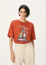 Remera color ladrillo con estampa de un velero y texto "Sunshine Sail Yatch Club".