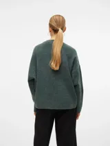 Sweater de punto grueso color verde con cuello redondo y hombros caídos. Tiene ajuste holgado y puños acanalados.