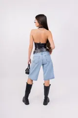 Top negro de cuero sintético con escote halter y cordones cruzados en el frente.