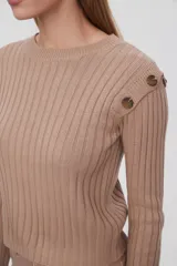 Sweater marrón de punto acanalado con cuello redondo y mangas largas. Presenta botones decorativos en los hombros.