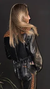 Campera corta de cuero negro, estilo torera, con animal print y flecos en la espalda.