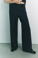 Pantalón negro de pierna ancha confeccionado en tejido de punto canalé con algodón. Tiene tiro medio y cintura con elástico interior.