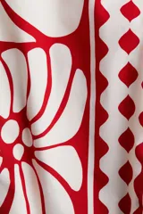 Top cropped de popelina de algodón color blanco con estampado floral y geométrico en rojo. Tiene escote recto, breteles elásticos y espalda fruncida.