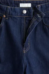 Pantalón de jean azul oscuro de tiro alto, corte recto y pierna ancha. Diseño de cinco bolsillos con costuras a la vista. Inspirado en los años 70.