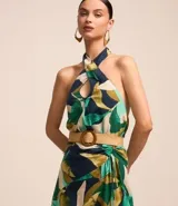 Blusa sin mangas con escote halter, estampado de follaje en tonos verde, azul y beige, y cinturón marrón.