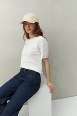 Remera blanca de algodón liviano, de manga corta y cuello redondo. Presenta costuras a contratono visibles en hombros y mangas.