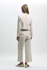 Pantalón tobillero negro de tiro alto con cinturón de cadena dorada. Presenta falsos bolsillos con solapa en la espalda, pernera recta y cierre lateral con cremallera oculta.