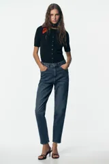 Pantalón de jean negro de corte recto, tiro alto y largo tobillero.