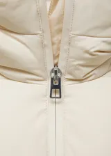 Campera puffer larga color beige, con capucha, cierre frontal con cremallera y bolsillos laterales con cierre.