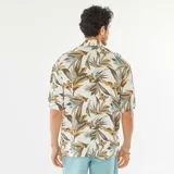 Camisa de manga corta blanca con estampado de hojas en tonos marrones, verdes y amarillos. Tiene cuello clásico, cierre frontal con botones y corte recto.