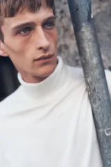 Polera blanca de punto fino, con cuello alto, mangas largas y corte ajustado.
