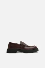 Mocasín de cuero color marrón oscuro, con antifaz y suela track de goma negra.