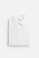 Camisa blanca de corte slim fit, confeccionada en algodón, con cuello italiano, mangas largas con puños abotonados y cierre frontal con botones.