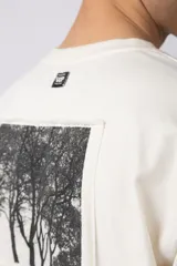 Remera color crudo, corte oversize, mangas cortas y cuello redondo. Estampado frontal con dos árboles unidos por sus raíces y parche estampado en la espalda con una silueta de mano que se fusiona con ramas.