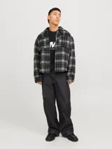 Sobrecamisa corta de manga larga con cuello sport, cierre frontal de cremallera, puños con botones, solapa cortaviento, bolsillos en pecho y delanteros. Diseño a cuadros grises y negros.