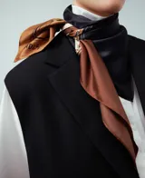 Pañuelo cuadrado de poliéster reciclado con estampado cartográfico en bloques de color naranja, rojo, bordó y gris. Presenta el logo de Adolfo Dominguez y detalles de texto inspirados en mapas.