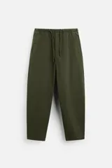 Pantalón verde militar de corte carrot fit, confeccionado en tejido de algodón. Tiene cintura elástica ajustable con cordón, bolsillos frontales y un bolsillo trasero de plastrón.