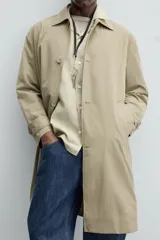Gabardina color beige de corte recto, con cuello solapa, cierre frontal con botones, bolsillos laterales y puños ajustables con trabilla.