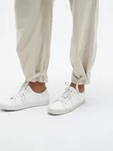 Pantalón color beige claro, de corte holgado, con bolsillos laterales y cinturón con hebilla metálica.