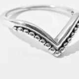 Anillo de plata 925 con forma de V y detalle de pequeñas esferas en los bordes.