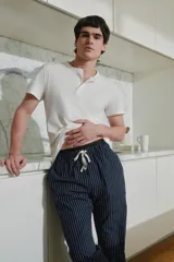 Conjunto de pijama para hombre, compuesto por una remera blanca de manga corta y un pantalón largo azul marino a rayas verticales blancas.