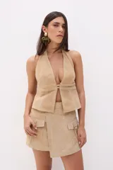 Top halter de cuero color beige, con escote profundo en V y cierre frontal con tiras horizontales.