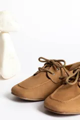 Mocasines color marrón claro con cordones y detalle de costuras en la puntera.