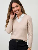 Buzo de hilado fino color beige con cuello y ruedo de gasa blanca que simula una camisa debajo. Presenta escote en V y mangas largas.