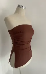 Top sin tirantes color marrón, con ajuste ceñido y diseño fruncido.