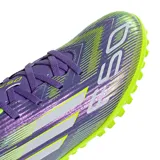 Championes de fútbol Adidas F50 Club para césped sintético. Diseño en tonos violeta y verde neón con detalles en blanco.