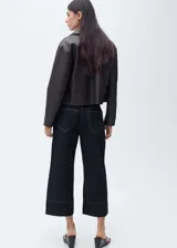 Pantalón de jean azul oscuro, corte cropped wide leg, tiro medio, con bolsillos delanteros y traseros, cierre frontal con cremallera y botón, y costuras a la vista.