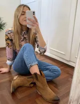 Botas cortas negras de cuero con bordados blancos estilo cowboy.