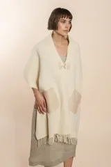 Chal de lana fina sin teñir, con calce en hombros, abrochadura con alamar de fieltro, bolsillos de cuero y terminación con flecos. Diseño exclusivo de Don Baez, hecho en Uruguay.